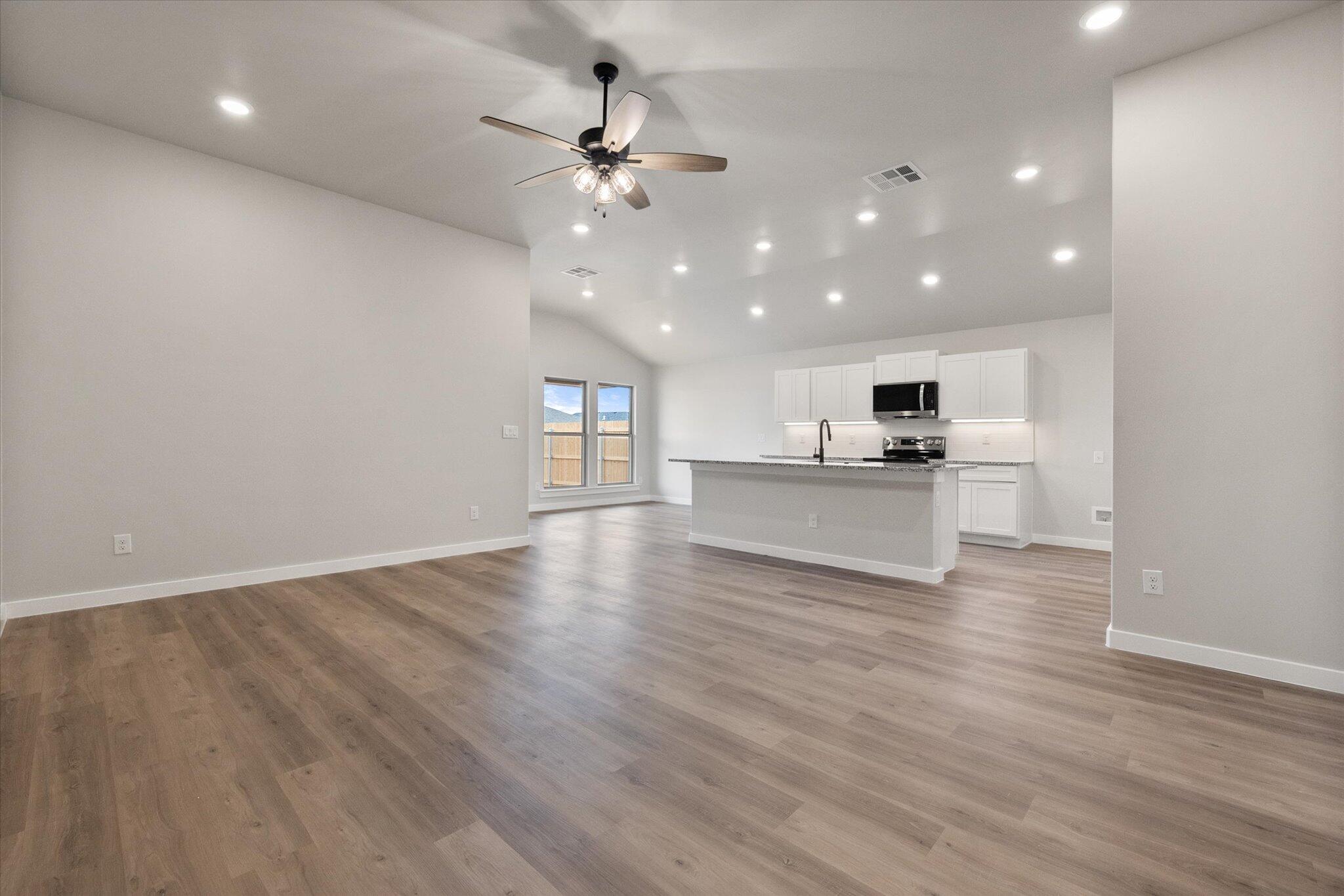 2332 136th Street Lubbock, TX 79423 - Photo 3 of 19 an empty room with wooden floor and kitchen view