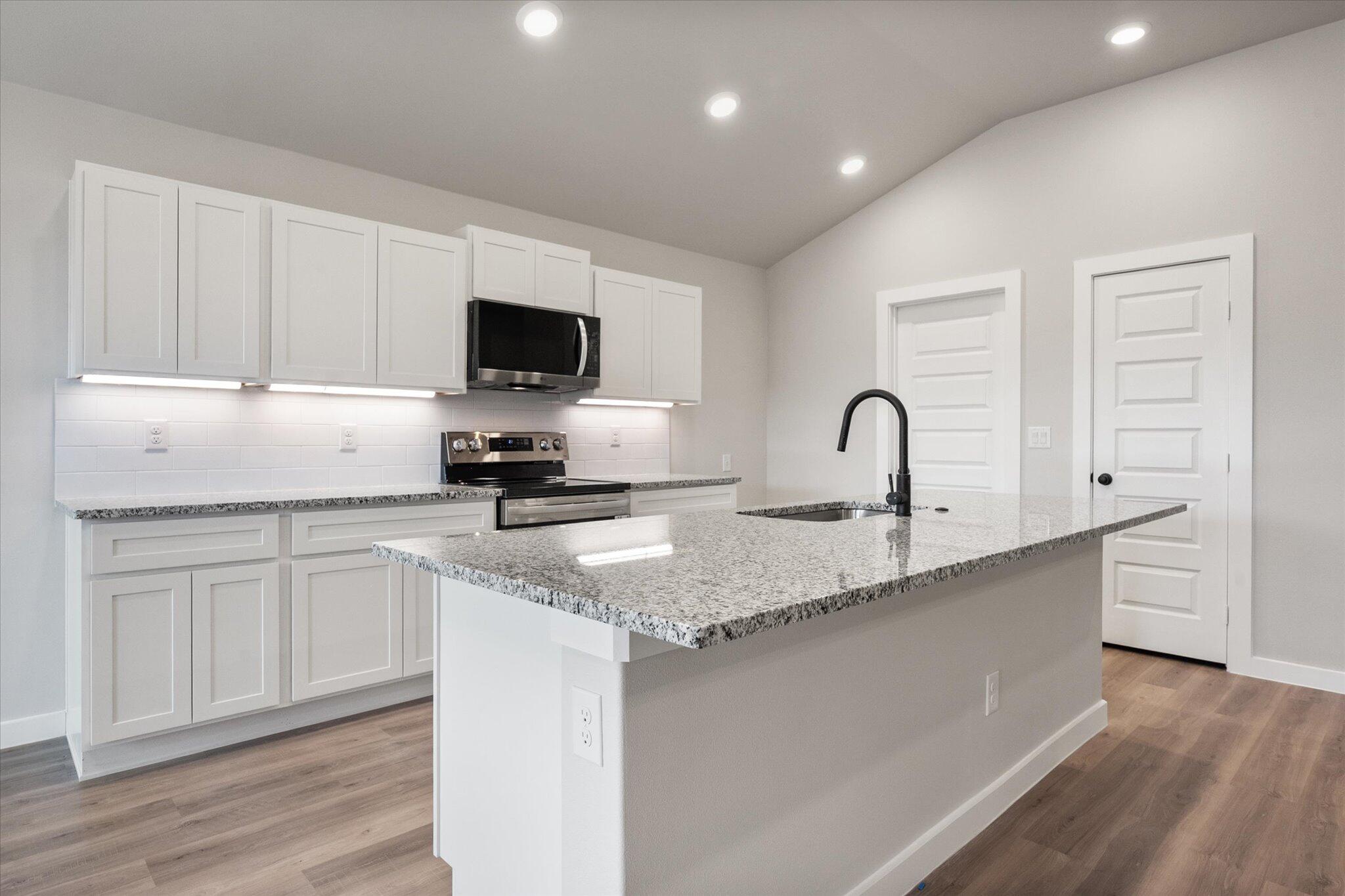 2332 136th Street Lubbock, TX 79423 - Photo 7 of 19 a kitchen with a sink white cabinets and black stainless steel appliances