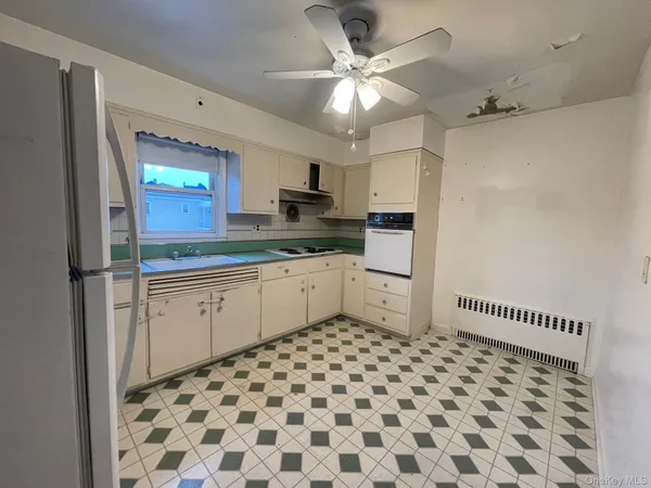 a kitchen with a sink a refrigerator and white cabinets