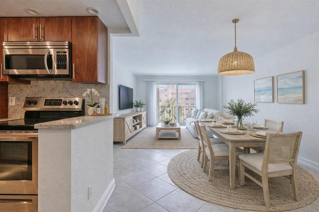 a kitchen with stainless steel appliances granite countertop a stove a microwave a sink a dining table and chairs with wooden floor