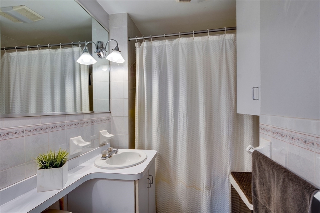 30 Kilsythe Road Arlington, MA 02476 - Photo 23 of 31 a bathroom with a sink a mirror and a shower curtain