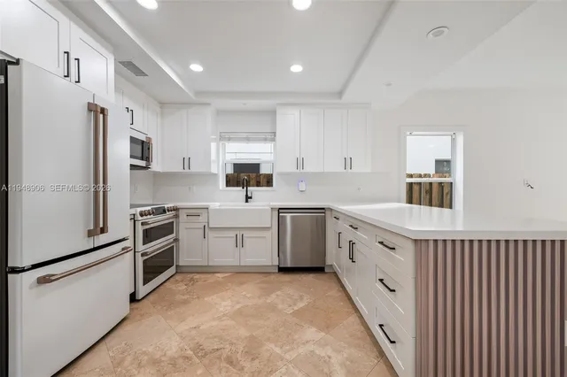 a kitchen with granite countertop a sink stove refrigerator and white cabinets with wooden floor