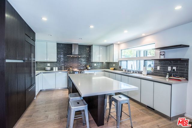 a kitchen with stainless steel appliances granite countertop a table chairs sink refrigerator and cabinets