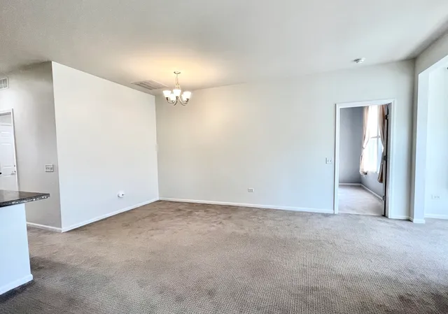 an empty room with a bathroom and a chandelier fan