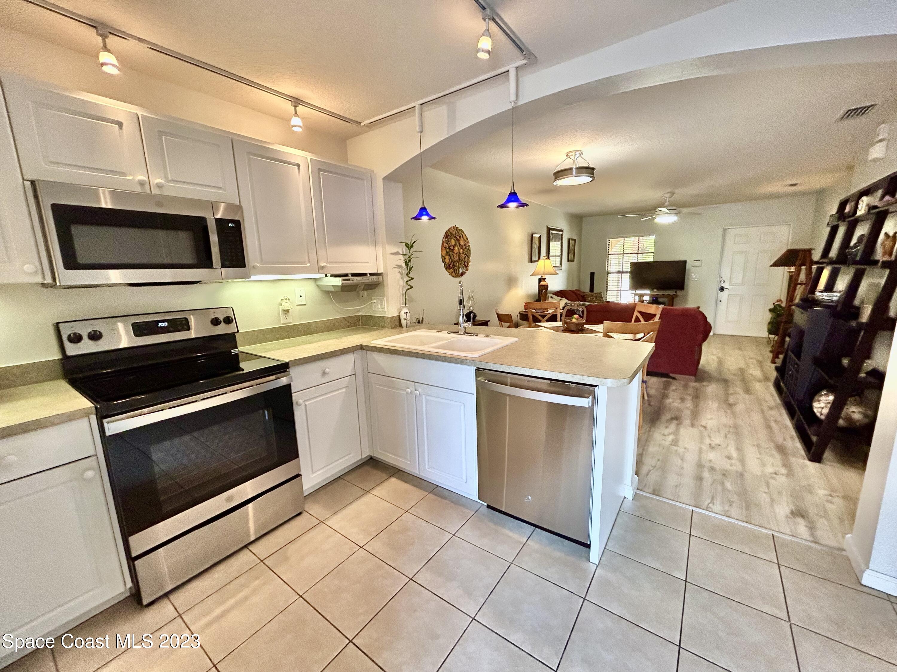1160 Luminary Circle, Unit 105 Melbourne, FL 32901 - Photo 14 of 35 a kitchen with stainless steel appliances granite countertop a sink dishwasher stove and white cabinets with wooden floor