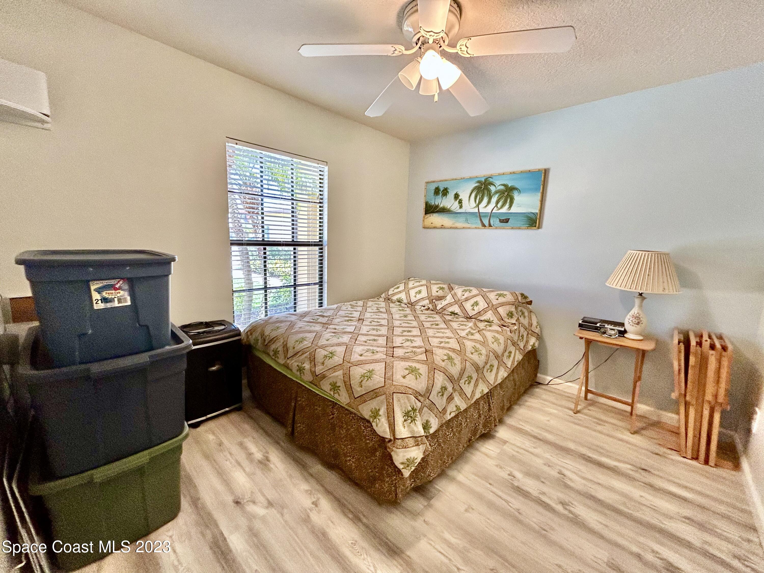 1160 Luminary Circle, Unit 105 Melbourne, FL 32901 - Photo 29 of 35 a bedroom with a bed and dresser with wooden floor