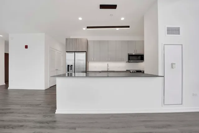 a large white kitchen with kitchen island sink and refrigerator