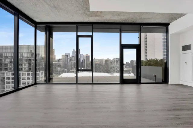 a view of an empty room with wooden floor and glass door