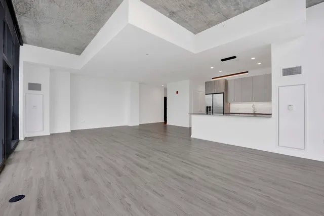 a view of kitchen and empty room with wooden floor