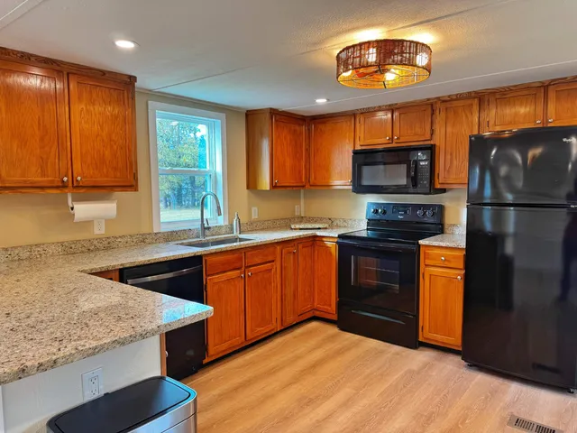 a kitchen with stainless steel appliances granite countertop a stove a sink dishwasher a refrigerator and a microwave oven with wooden floor