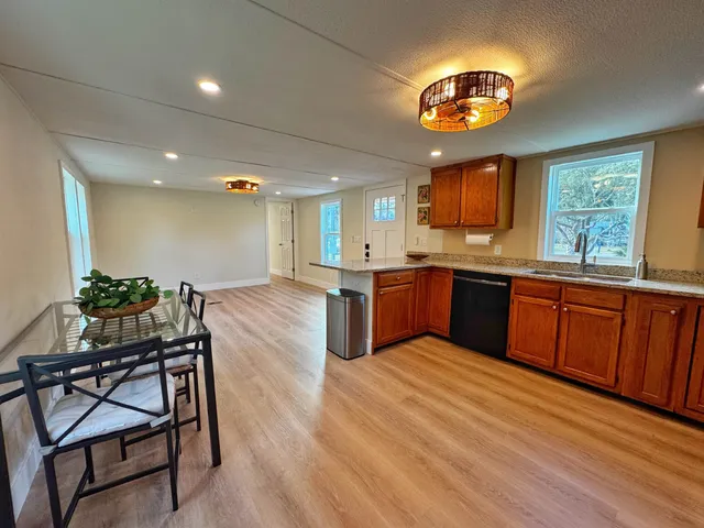 a kitchen with stainless steel appliances granite countertop wooden cabinets a stove a sink and a wooden floors