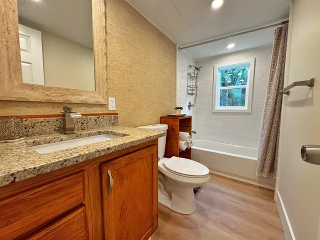 a bathroom with a granite countertop sink a toilet a mirror and bathtub