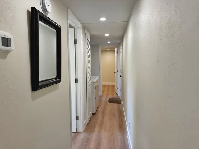 a view of a hallway with wooden floor and a bathroom