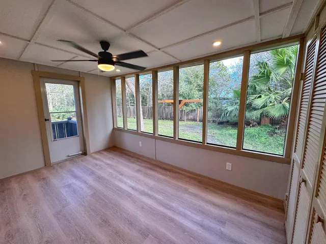 a view of a livingroom with a large window wooden floor and brick walls