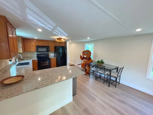 a kitchen with stainless steel appliances granite countertop a sink a stove and a wooden floors