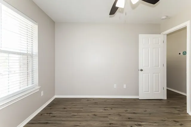 a view of an empty room with a window and wooden floor