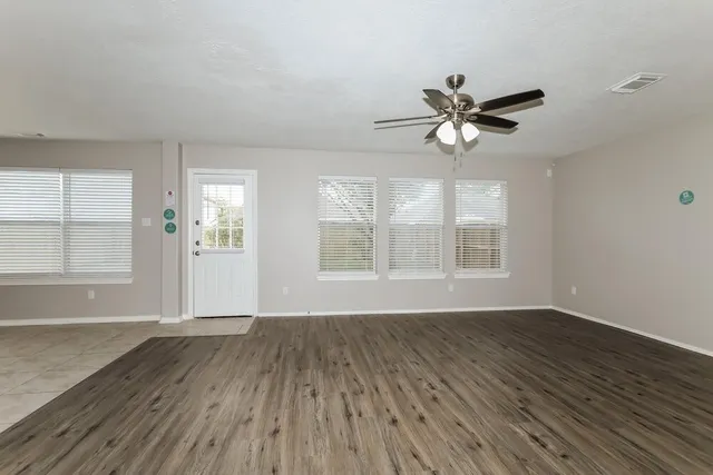 a view of an empty room with wooden floor and a fireplace