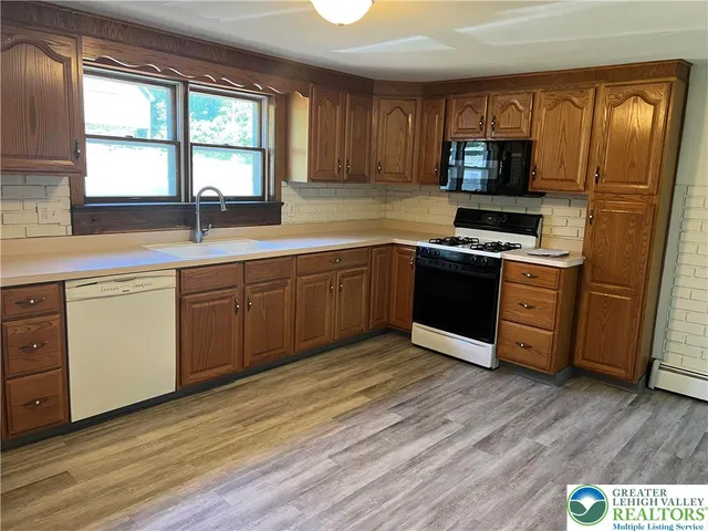 a kitchen with stainless steel appliances granite countertop a stove a sink dishwasher a refrigerator and a microwave oven with wooden floor