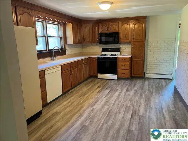 a kitchen with stainless steel appliances a stove top oven a sink and a granite counter tops with wooden floors