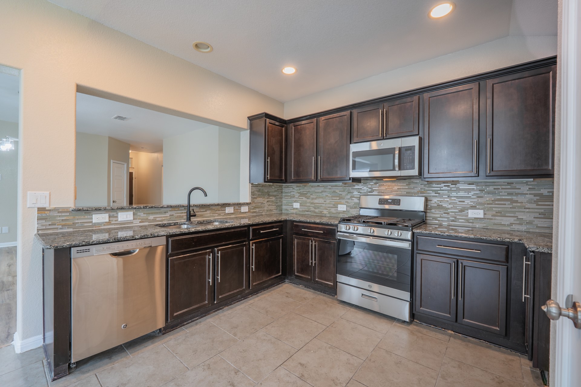 624 Joppa Road Leander, TX 78641 - Photo 10 of 36 a kitchen with stainless steel appliances granite countertop a stove sink and cabinets