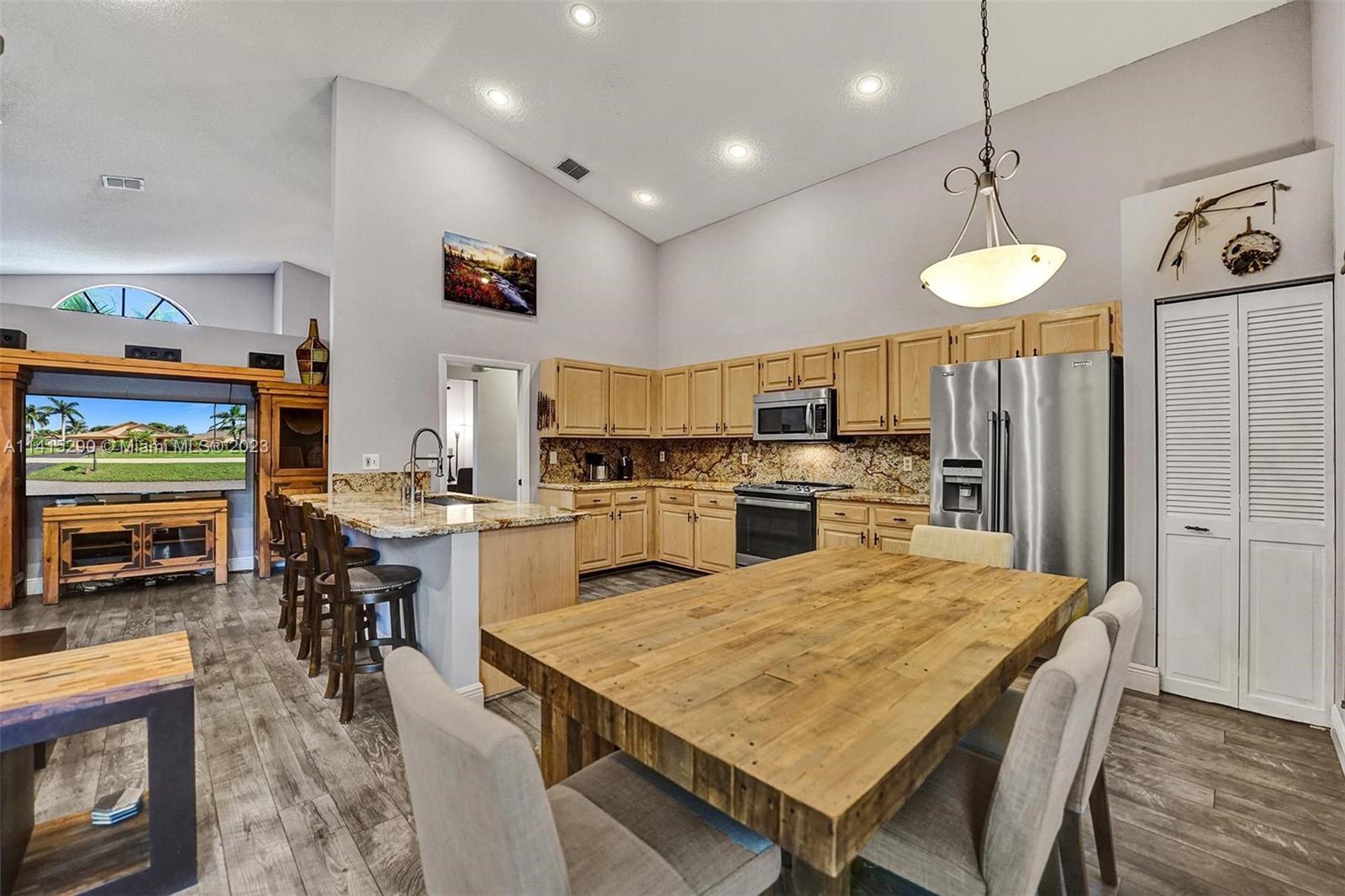 9641 Ridgeside Court Davie, FL 33328 - Photo 24 of 78 a kitchen with stainless steel appliances kitchen island granite countertop a table chairs and a refrigerator