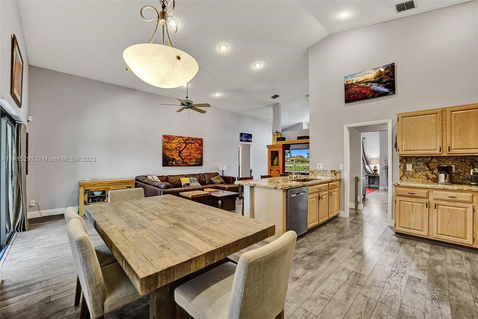 9641 Ridgeside Court Davie, FL 33328 - Photo 25 of 78 a kitchen with a stove a refrigerator a sink dishwasher with a dining table and chairs with wooden floor