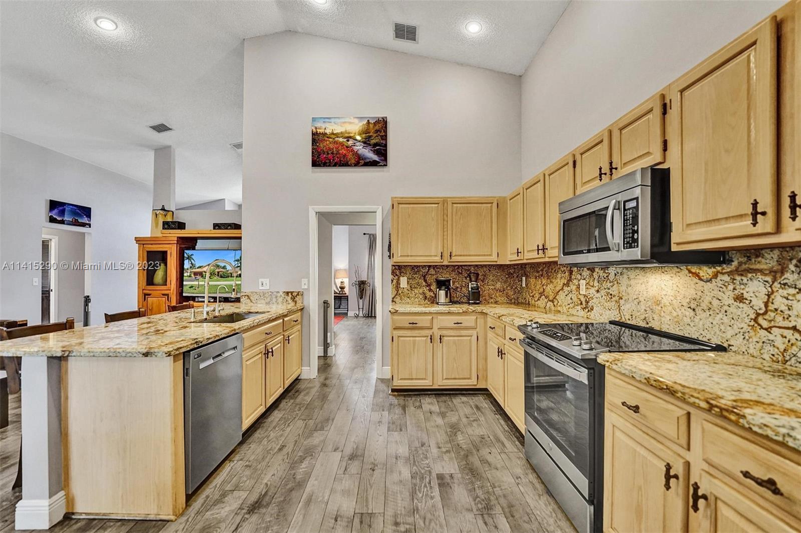 9641 Ridgeside Court Davie, FL 33328 - Photo 26 of 78 a kitchen with stainless steel appliances granite countertop a stove top oven a sink dishwasher and white cabinets with wooden floor