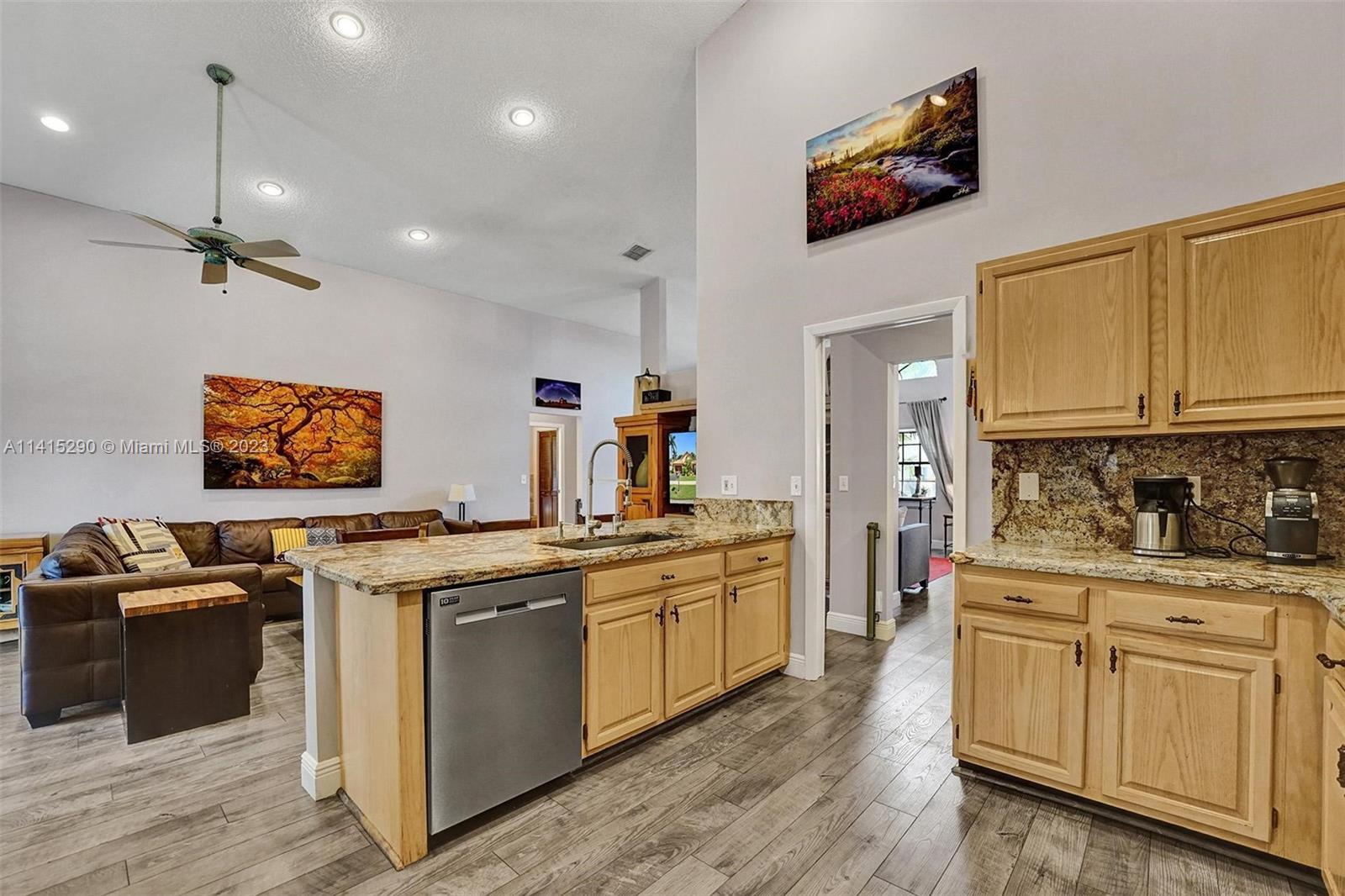 9641 Ridgeside Court Davie, FL 33328 - Photo 27 of 78 a kitchen with stainless steel appliances granite countertop a stove a sink dishwasher and a refrigerator with wooden floor