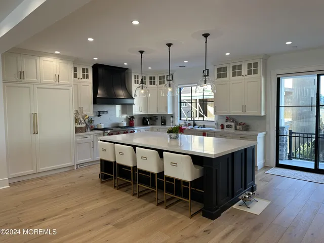 a large kitchen with stainless steel appliances kitchen island granite countertop a table chairs sink and wooden floor