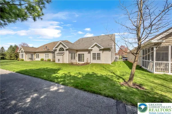 a view of a white house with a big yard and potted plants and large trees