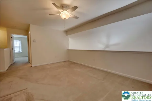 an empty room with a chandelier fan and windows
