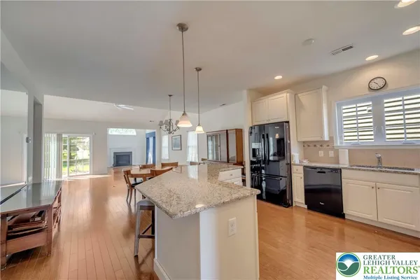 a kitchen with stainless steel appliances granite countertop a refrigerator a oven a sink dishwasher and a stove with wooden floor