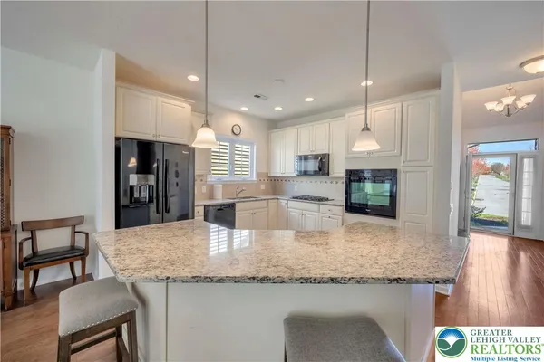 a kitchen with granite countertop kitchen island stainless steel appliances a sink and a refrigerator