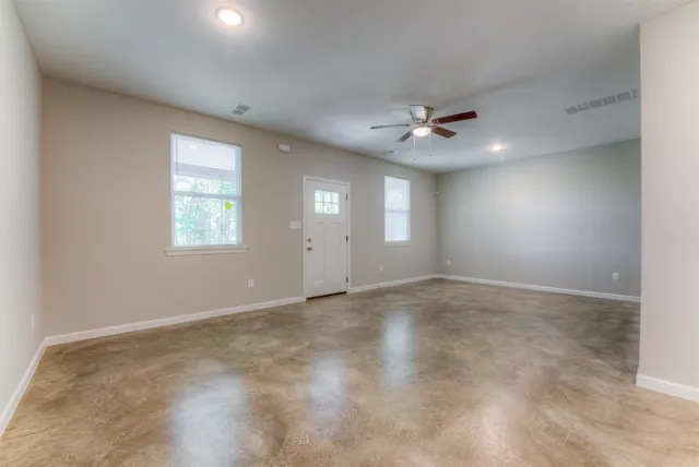 an empty room with windows and ceiling fan