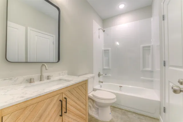 a bathroom with a bathtub shower sink vanity mirror and toilet