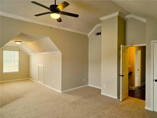 an empty room with ceiling fan and windows