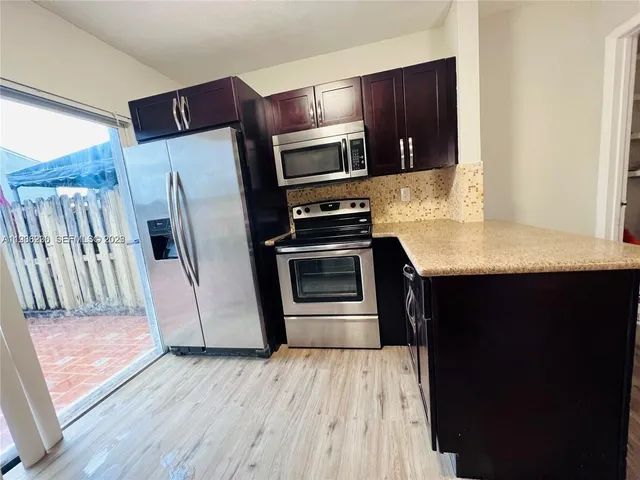 a kitchen with stainless steel appliances granite countertop a refrigerator a stove and a microwave oven