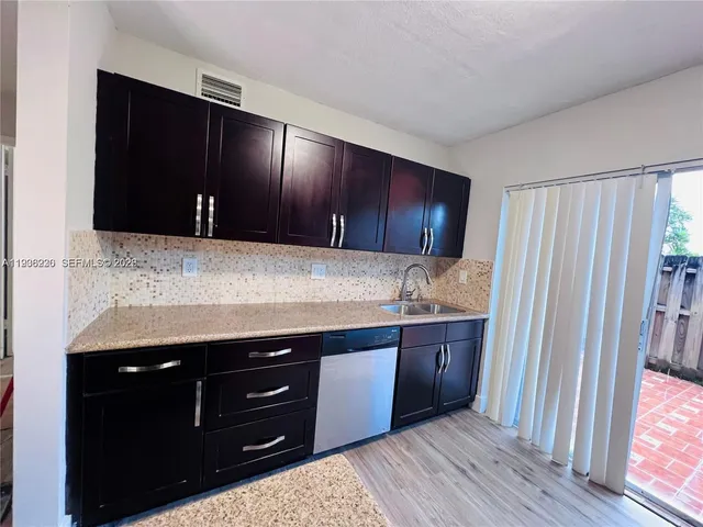 a kitchen with stainless steel appliances granite countertop wooden cabinets and a wooden floor