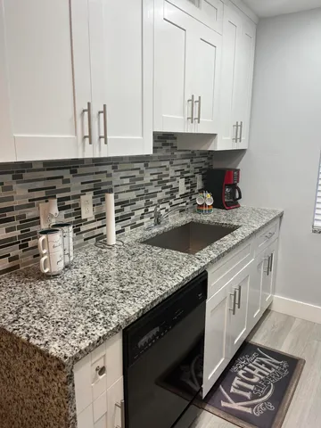 a kitchen with granite countertop a sink a stove and cabinets