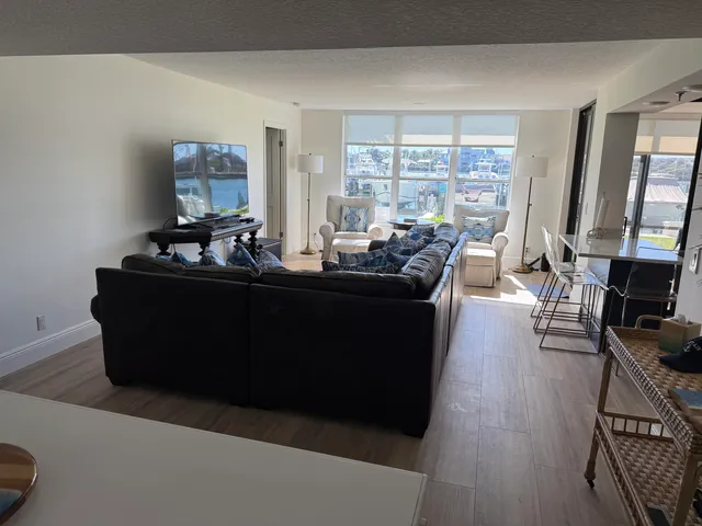 a living room with couches and a flat screen tv with kitchen view