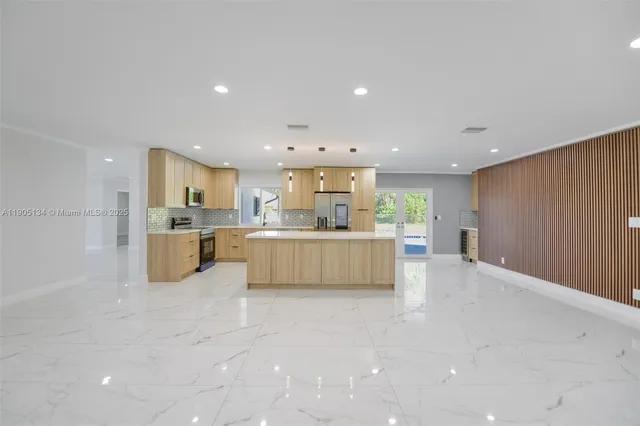 a large white kitchen with kitchen island a sink a center island stainless steel appliances and a fireplace