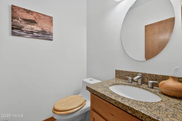 a bathroom with a granite countertop toilet a sink and mirror