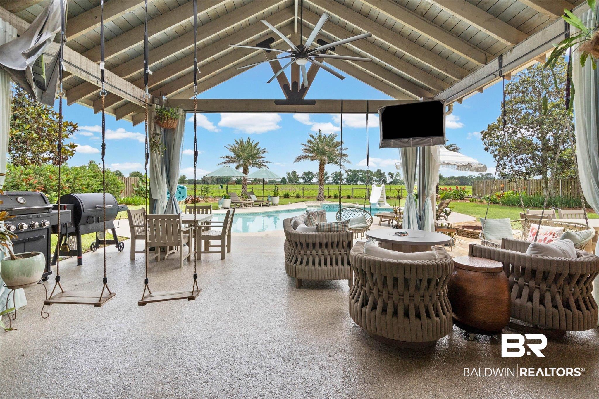 24908 Bosbyshell Avenue Daphne, AL 36526 - Photo 5 of 49 Expansive covered patio featuring a vaulted wood-beam ceiling, textured concrete flooring, and a ceiling fan