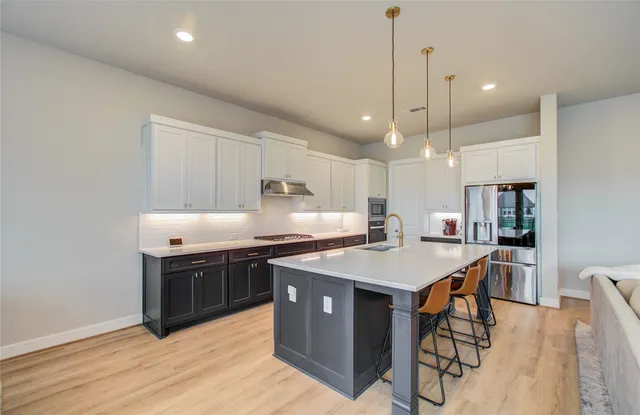 a kitchen with stainless steel appliances granite countertop a stove a sink dishwasher and a refrigerator with wooden floor