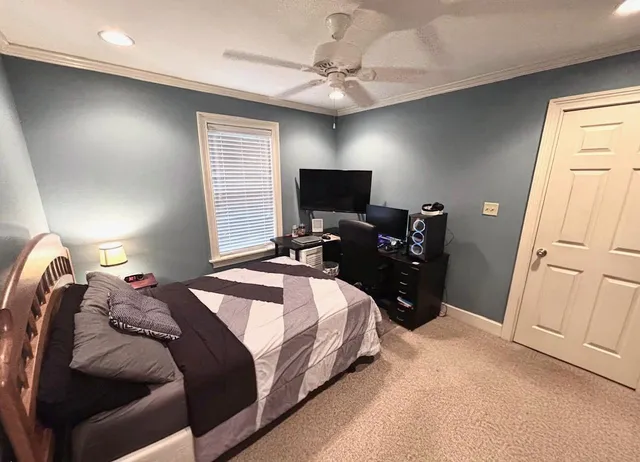 a bedroom with a bed and a flat tv screen on dresser