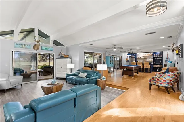 a living room with furniture kitchen view and a chandelier