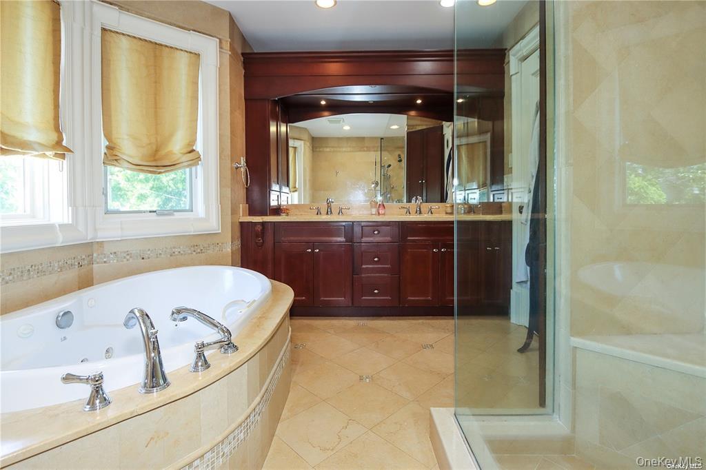 24 Steamboat Road Great Neck, NY 11024 - Photo 19 of 28 Full bath featuring double vanity, a whirlpool tub, a shower stall, and light tile patterned floors