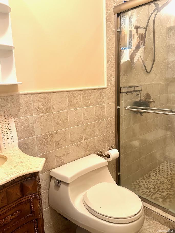 24 Steamboat Road Great Neck, NY 11024 - Photo 25 of 28 Full bathroom with vanity, tile walls, and a stall shower