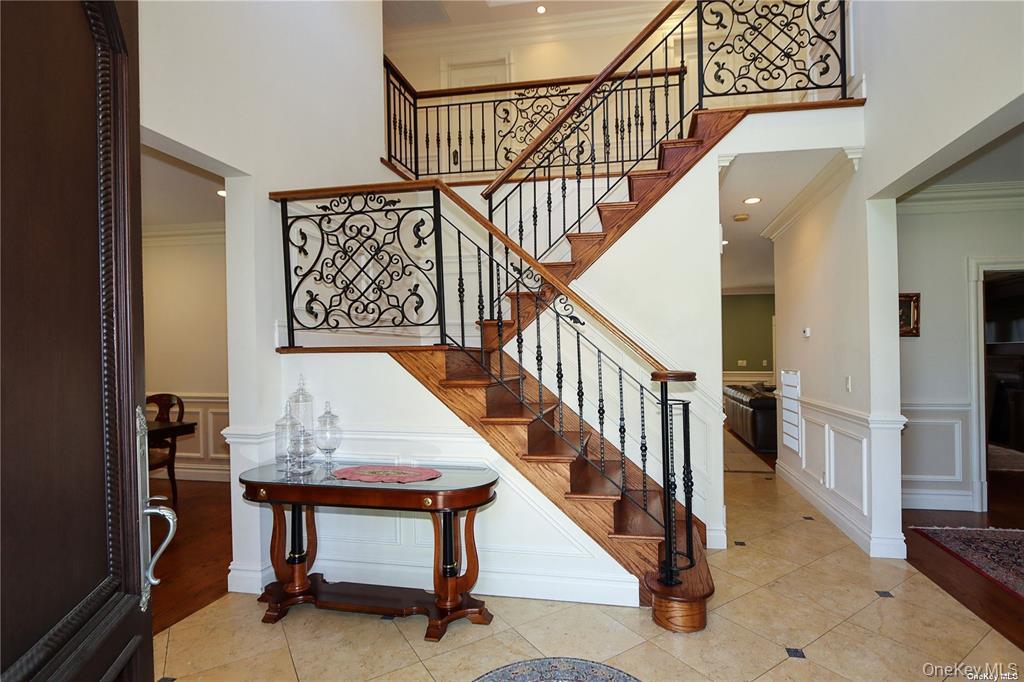 24 Steamboat Road Great Neck, NY 11024 - Photo 3 of 28 Stairway with ornamental molding, tile patterned floors, a towering ceiling, and a decorative wall