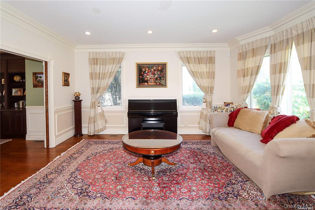 24 Steamboat Road Great Neck, NY 11024 - Photo 4 of 28 Living area featuring wood finished floors, healthy amount of natural light, crown molding, wainscoting, and recessed lighting